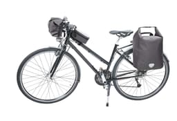 A black bicycle with a handlebar bag and two side bags, all in dark fabric. The bike has a sleek design.
