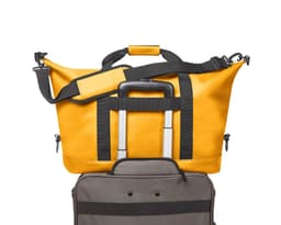 A yellow duffle bag with black straps sits atop a grey suitcase, featuring a logo on the bag.