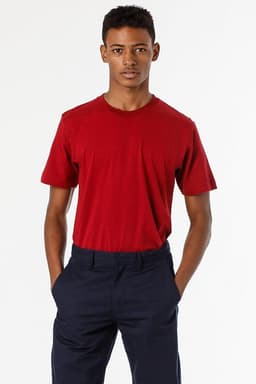 A model wearing a red short sleeve fine jersey crew tee paired with navy trousers, featuring a logo on the shirt.