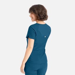 A back view of a blue Embrace Luna Tuckable Y-Neck Top, featuring short sleeves and a logo.