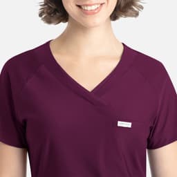 A purple Y-neck top featuring a pocket and a logo, designed for a comfortable fit.