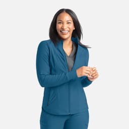A full zip track jacket in teal, featuring a fitted design and zippered pockets, worn by a smiling woman.