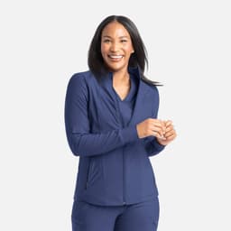 A full zip track jacket in navy blue, featuring a high collar and a fitted design. The model is smiling and wearing it.