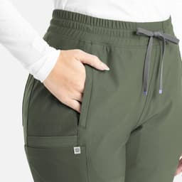 A close-up of olive green bootcut pants featuring an elastic waistband and side pockets, with a logo on the pocket.