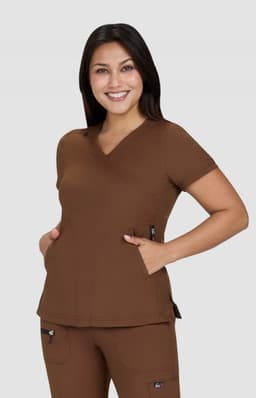 A brown medical top with a relaxed fit, featuring a V-neck and pockets, worn by a smiling model.