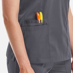 A women's double V-neck top in grey with two pens in the side pocket. It features a logo on the fabric.