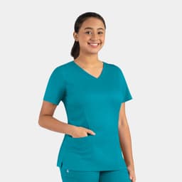 A woman smiles while wearing a teal double V-neck top with a pocket on one side. The top features a fitted design.
