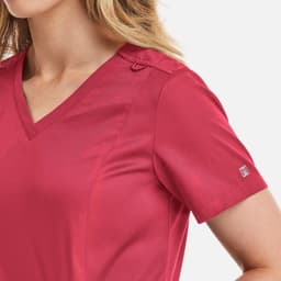 A women's double V-neck top in a vibrant pink shade with a logo on the sleeve.