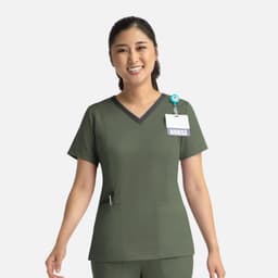 A nurse in an olive green double V-neck top with a dark trim, featuring a badge and logo.