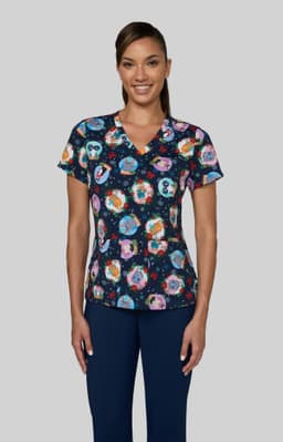 A patterned scrub top featuring vibrant illustrations on a navy background, paired with navy pants.