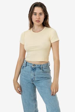 A model wearing a mid-length baby rib crewneck tee in a light yellow colour, paired with blue jeans.