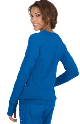 A woman wearing a bright blue Clarity Jacket, viewed from the back, smiling at the camera.