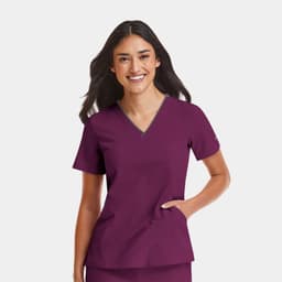 A woman is wearing a women's burgundy V-neck top with a grey contrast, featuring a logo.