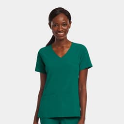 A women's mock wrap top in teal green with a v-neckline and two front pockets. The model is smiling.