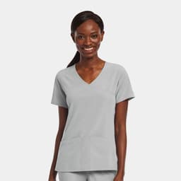 A woman wearing a light grey mock wrap top with two front pockets and a v-neckline.