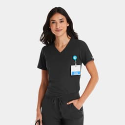 A women's black V-neck top with a pocket, worn with a badge holder. The top has a logo on it.