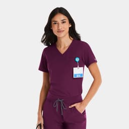 A women's tuckable v-neck top in deep burgundy, featuring a logo and a badge holder.