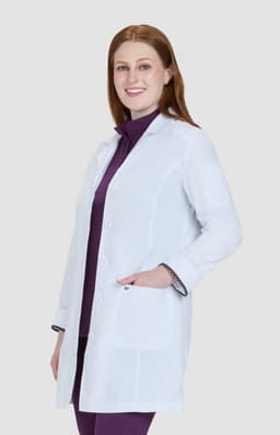A white lab coat with a tailored fit, displayed on a model wearing a purple top underneath. The coat features pockets and a logo.