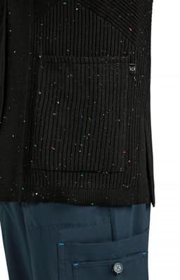 A black Kori Sweater featuring a textured design and a front pocket, paired with navy blue trousers.