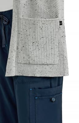 A grey Kori Sweater with a ribbed texture and a pocket, displayed alongside navy pants.