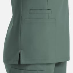 A women's double V-neck top in a soft green colour, featuring pockets and side slits for comfort. It has a logo.