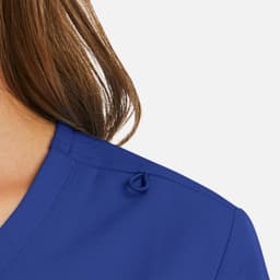 A close-up of a blue women's mock wrap top featuring a decorative tie detail on the shoulder.