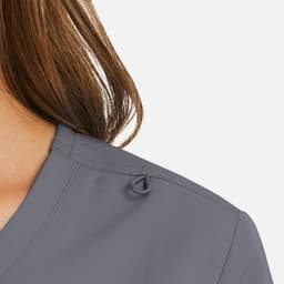 A close-up of a women's mock wrap top in grey, featuring a decorative loop detail on the shoulder.
