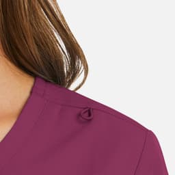 A close-up of a women's mock wrap top in a rich plum colour, featuring a loop detail on the shoulder.