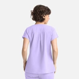 A lilac women's top featuring a back pleat and short sleeves, with a branding logo on it.