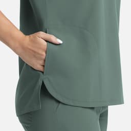 A green women's top featuring a dolman sleeve design and a side pocket. The fabric has a smooth finish.