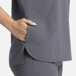 A grey women's top features a rounded hem and a side pocket, showcasing a sleek and comfortable design.