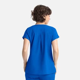 A blue women's Dolman top featuring three pockets, shown from the back on a model with curly hair.