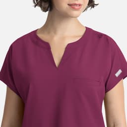 A women's dolman top in a rich plum colour, featuring a v-neck and a single pocket, with a logo on the sleeve.
