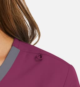 A close-up of a women's mock wrap top in a deep purple shade with grey contrast trim and a decorative detail on the shoulder.