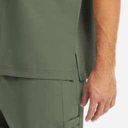 A close-up of a men's tuckable V-neck top in olive green, showing the fabric and a hand near the hem.