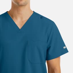 A men's v-neck top in teal with four pockets and a shoulder snap detail. Features branding on the sleeve.