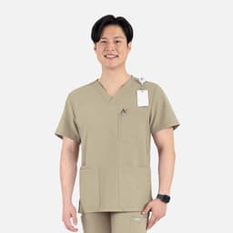 A men's V-neck top in a tan colour with four pockets and a logo, modelled by a man.