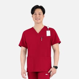 A man wearing a red V-neck top with four pockets, featuring a logo on the sleeve and a tag.