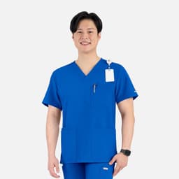 A male model wearing a blue v-neck top with four pockets and a logo on the chest.