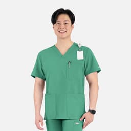 A green men's V-neck top featuring four pockets and a logo, modelled by a smiling individual.