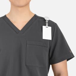 A grey V-neck top featuring contrast piping and a chest pocket, with a badge holder on the shoulder.