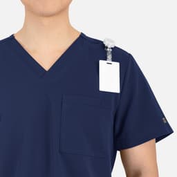 A navy V-neck top with contrast piping and a chest pocket, featuring a badge holder on the shoulder.