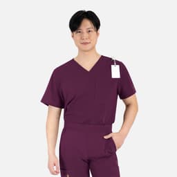 A male model in a burgundy V-neck top featuring a chest pocket and a tag. The fabric appears lightweight and comfortable.