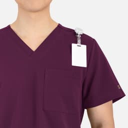 A burgundy V-neck top featuring contrast piping and a pocket, with a badge holder on the shoulder.