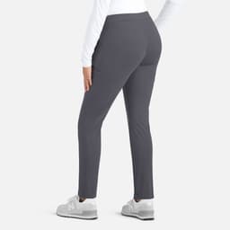 A woman wearing grey mid-rise tapered pants from the back, paired with a white long-sleeve top and grey sneakers.