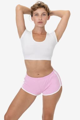 A model poses wearing pink interlock running shorts with white trims and a white crop top. The shorts have a logo.