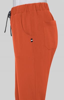 An orange pair of pants with an elastic waistband and side pockets, featuring a small logo on the side.