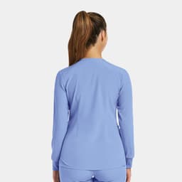 A women's round neck snap jacket in light blue, featuring a fitted design and long sleeves. It has a logo on the back.