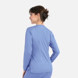 A woman wearing a light blue round neck snap jacket, viewed from the back. The jacket has a simple design and includes a logo.