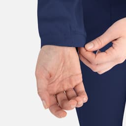 A close-up of a person's hand adjusting the cuff of a navy blue round neck jacket, featuring a logo.